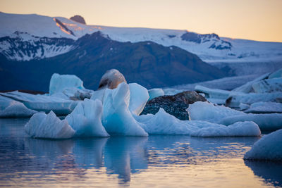 Scenic view of icebergs on lake against sky during sunset