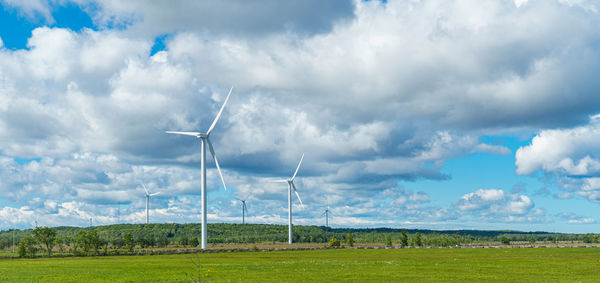 Windmills on field against sky