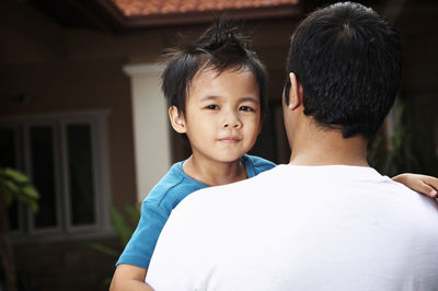 Close-up of father and carrying son at yard