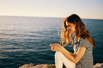 Young woman looking at sea against sky