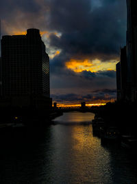 Scenic view of river by buildings against dramatic sky