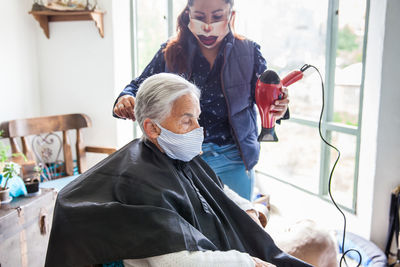 Beautician treating hair of customer at home