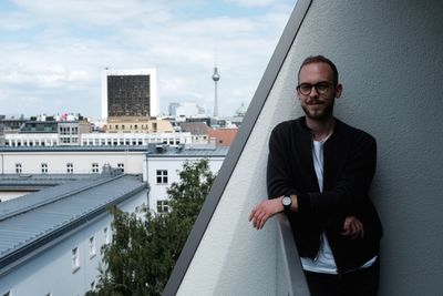 Portrait of young man wearing eyeglasses standing in balcony