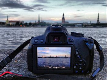 Close-up of camera on sea against cityscape