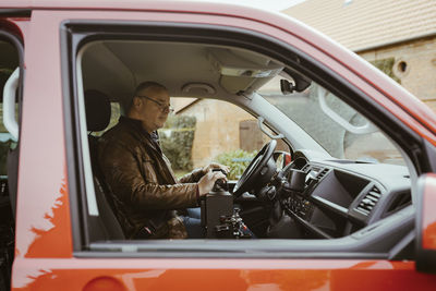 Retired senior man with disability sitting inside van