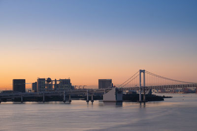 Bridge over sea against clear sky during sunset