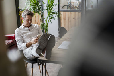 Businessman sitting with feet on desk using cell phone