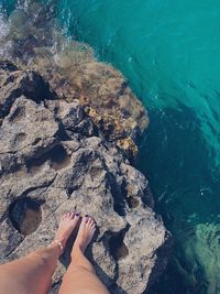 Low section of woman on rock by sea