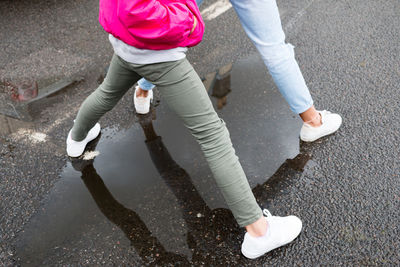 Low section of girl standing on wet road