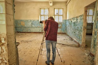 Full length of woman photographing in abandoned room