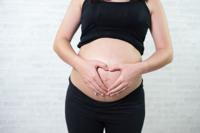 Midsection of pregnant woman touching stomach