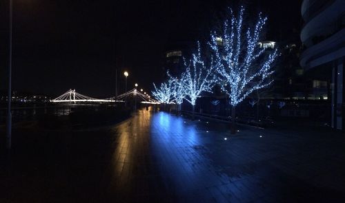 Illuminated bridge over river against sky at night