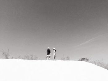 Rear view of men on snow field against sky
