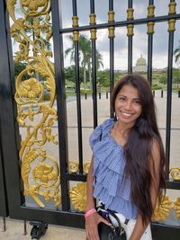 Portrait of smiling young woman standing against closed gate