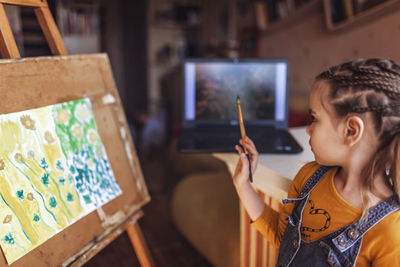 Side view of girl painting at home