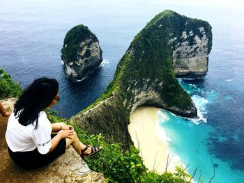Woman sitting on rock over sea
