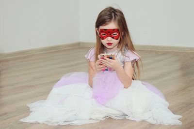 Girl wearing dress while using phone on hardwood floor