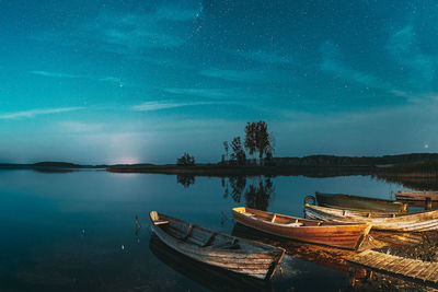Boats moored in lake against sky at night