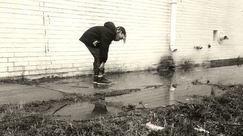 Girl scratching leg while standing on wet footpath in city