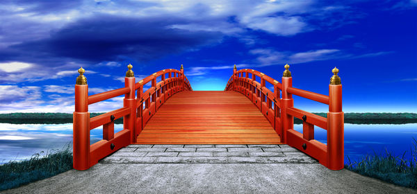 Bridge over calm blue sea against sky