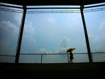 Woman holding umbrella while standing in stadium against sky