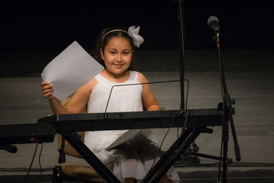 Portrait of smiling girl with piano on stage