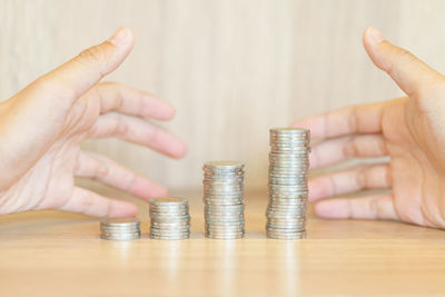 Cropped image of hand holding stack of coins on table