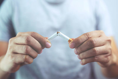 Midsection of man breaking cigarette