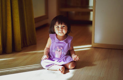 Portrait of boy sitting on hardwood floor at home