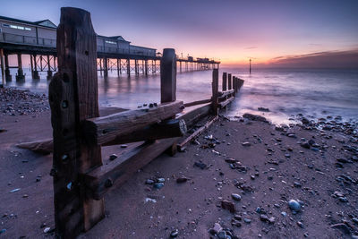Pier over sea against sky during sunset