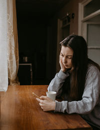 Side view of young woman sitting at home