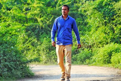 Thoughtful man walking on footpath against plants