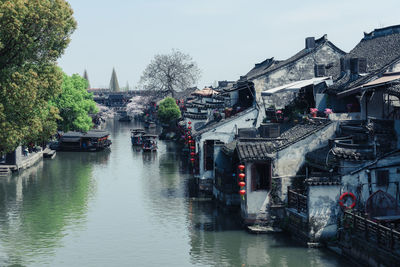 Boats in river amidst buildings in city against sky