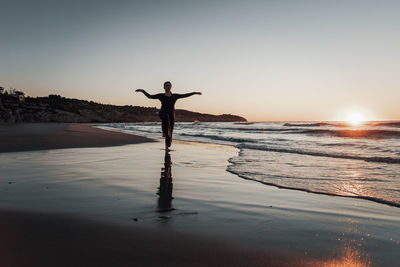 Woman standing on beach during sunrise