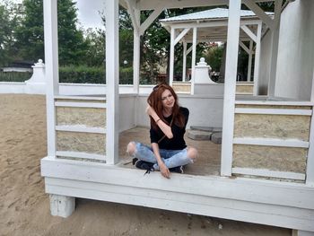 Smiling young woman sitting in gazebo at beach