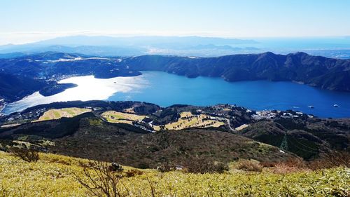 Scenic view of sea and mountains against blue sky