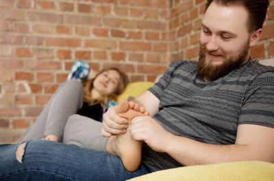 Man and woman sitting on sofa against wall