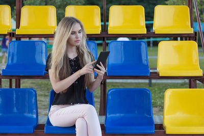 Young woman using digital tablet while sitting on chair