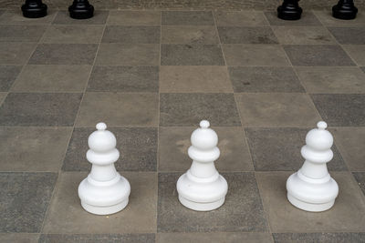 High angle view of chess pieces on tiled floor