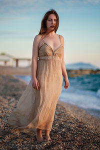 Portrait of beautiful woman standing on land against sky