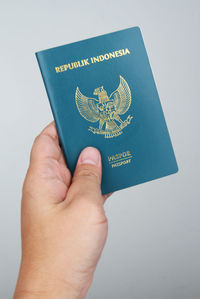 Close-up of hand holding paper against white background