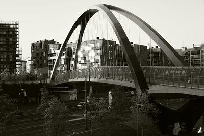 Bridge over river by buildings against clear sky