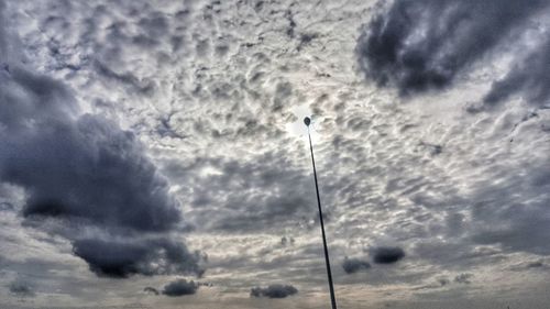 Low angle view of silhouette crane against dramatic sky