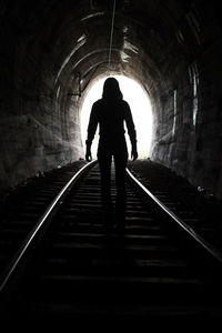 Rear view of silhouette man standing in tunnel