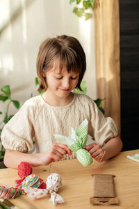 Making easter decorations. a girl makes a textile easter egg at home in the shape of a bunny, bunny.