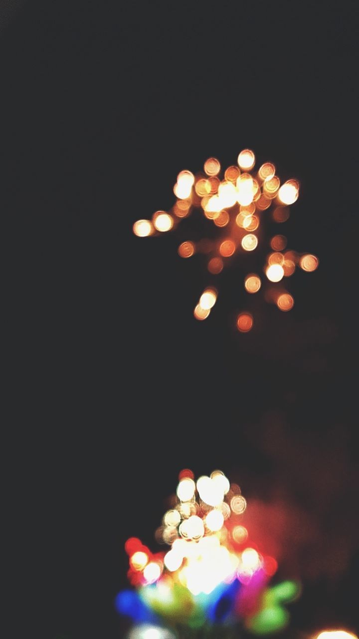 DEFOCUSED IMAGE OF ILLUMINATED CHRISTMAS LIGHTS AGAINST BLACK BACKGROUND