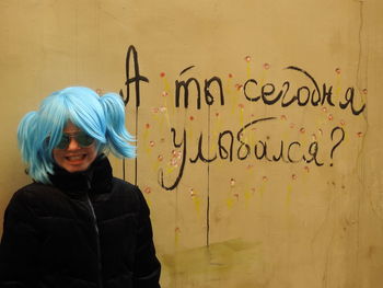 Portrait of young woman standing against wall