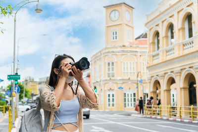 Asian traveler girl take a photo while walking on the city street in phuket thailand. travel concept