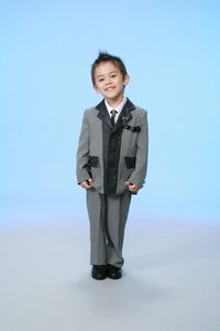 Full length portrait of boy standing against blue background