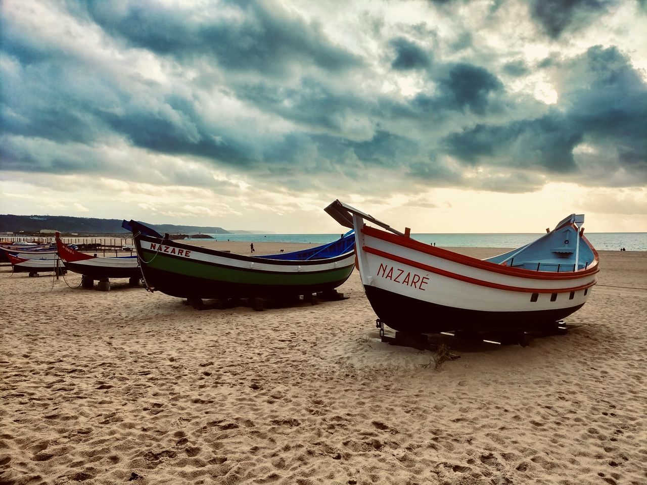 nautical vessel, beach, transportation, sky, water, mode of transportation, land, sand, cloud, sea, moored, boat, nature, long-tail boat, vehicle, shore, scenics - nature, tranquility, beauty in nature, no people, travel, tranquil scene, watercraft, outdoors, coast, travel destinations, rowboat, ocean, non-urban scene, sunset, wave, coastline, day, dramatic sky, landscape, holiday, boating, ship, absence
